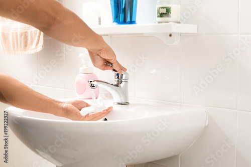Fototapeta Naklejka Na Ścianę i Meble -  Man washing hand under running water with liquid soap