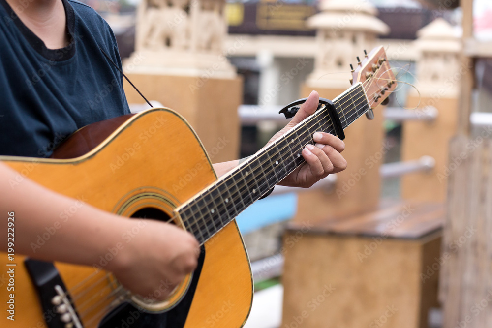 Fototapeta premium Man playing acoustic guitar with a capo clip