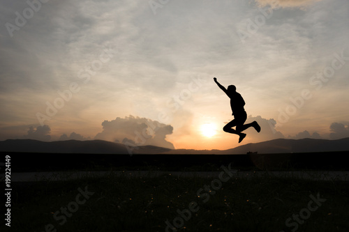 Silhouette of happy man jumping at sunset