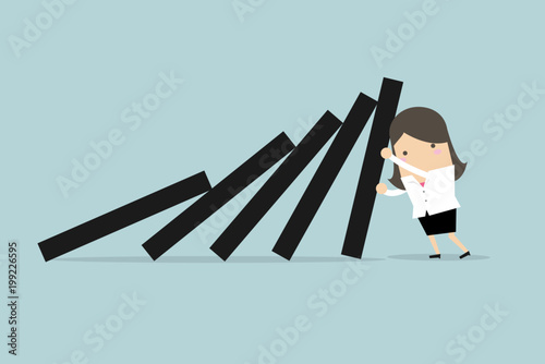 Businesswoman pushing hard against falling deck of domino tiles.