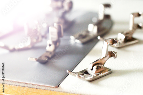 Group of sewing machine accessories. Various presser feet are used for different tasks and stem types.