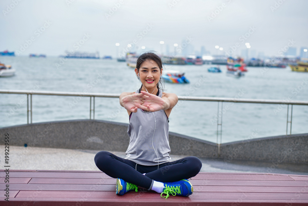 Sports concept. Beautiful girl is exercising on the beach with warm up. Beautiful girl is happy to exercise.