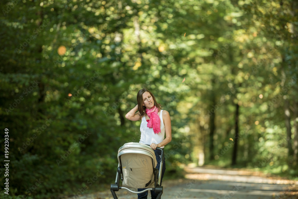 Woman pushing baby carriage in park Woman pushing baby carriage in park