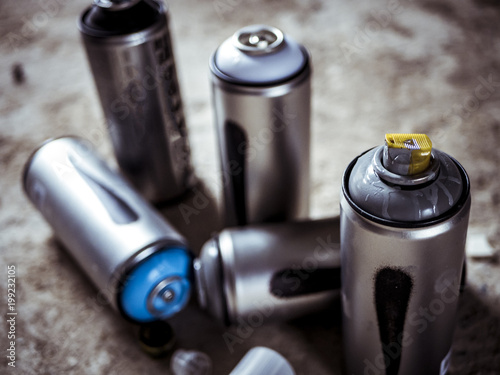 close macro shot of spray paint cans droped on the dusty ground
