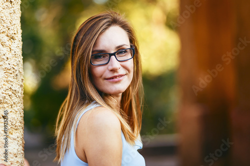 cheerful happy attractive young woman thirty years old with glasses on the street in summer