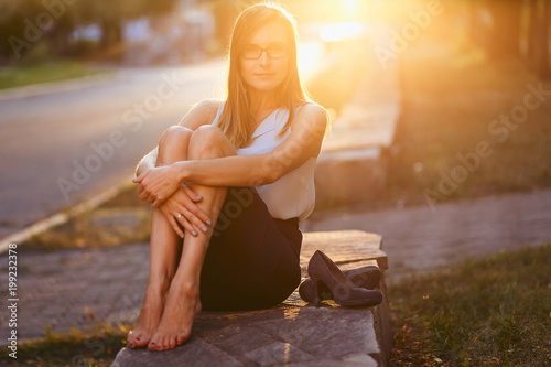 beautiful woman with glasses sitting in the Park in sunset light in summer