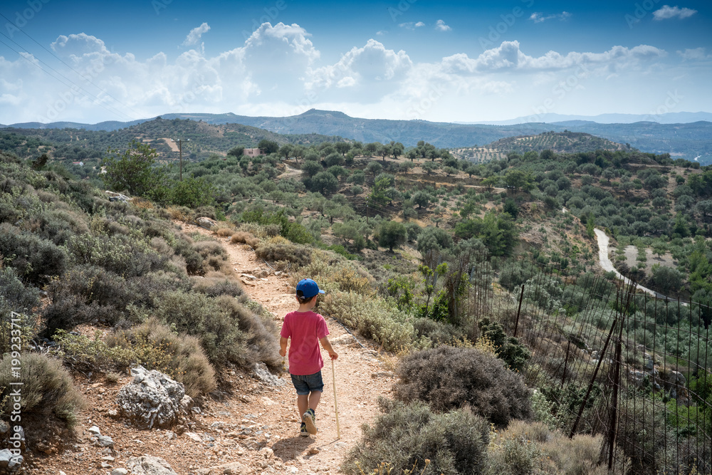 Boy hiking on path amidst field, Crete, Greece