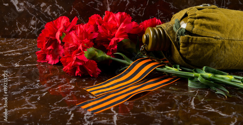 carnations, against the background of the monument, with the Gergiev ribbon and military flask photo