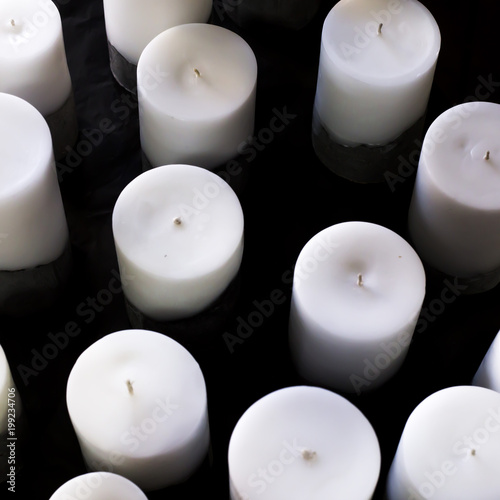 A lot of big white round candles of different size on a black background. Sale of minimalist candles for the interior