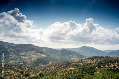 Field and mountain against cloudy sky