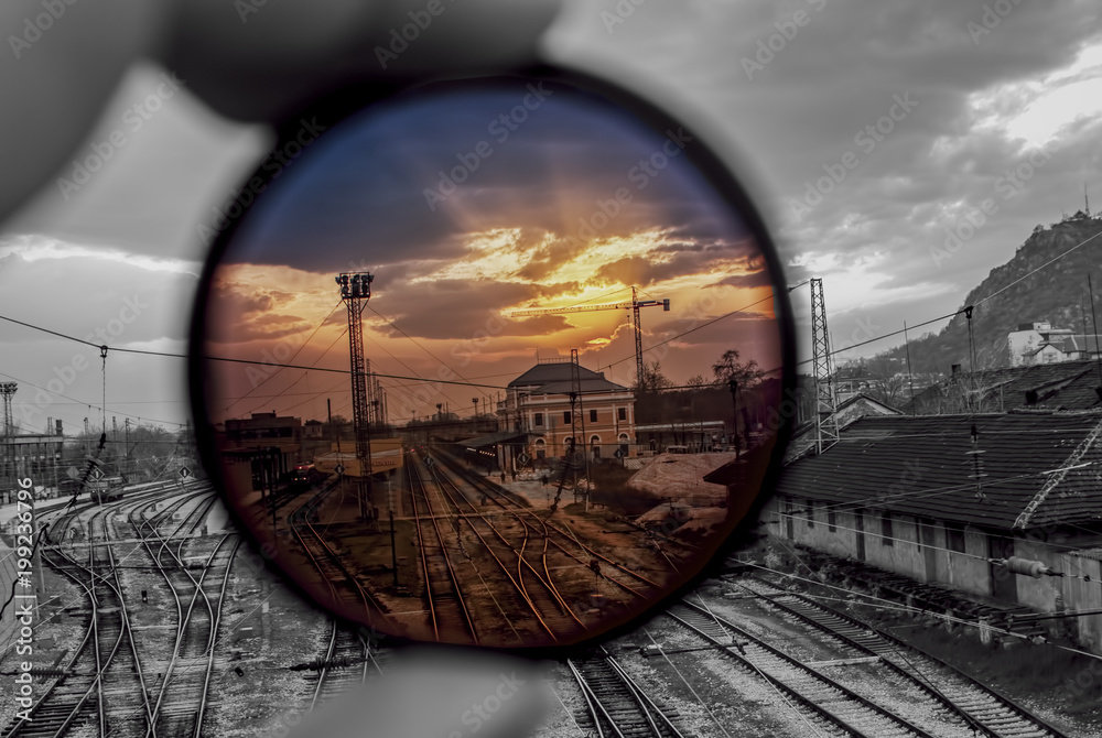 Man hold ND photographic filter on railway station at sunset