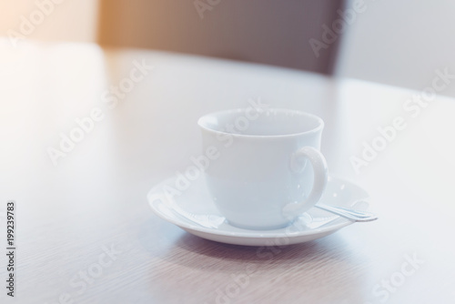 cup of hot tea and spoon on wooden table in meeting room - filter retro color tone