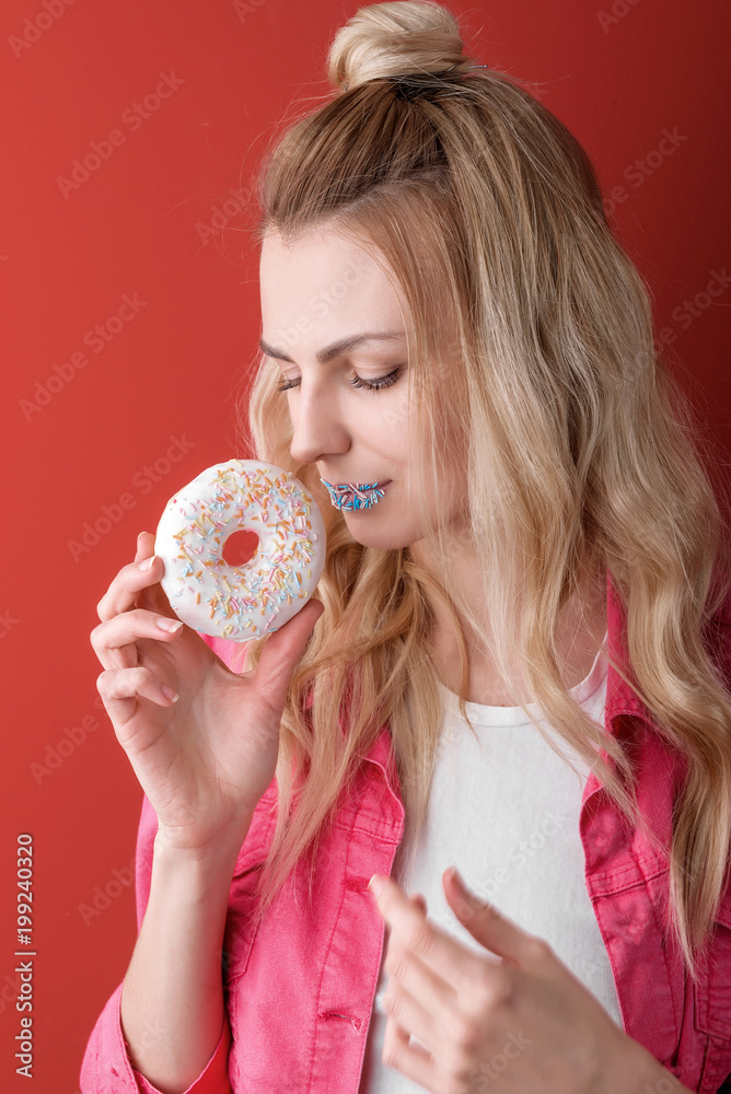 girl in pink jacket on red background with donut in hands girl in pink jacket on red background with donut in hands
