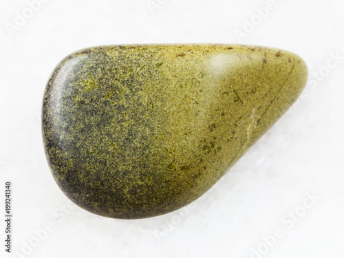 polished epidote gemstone on white marble