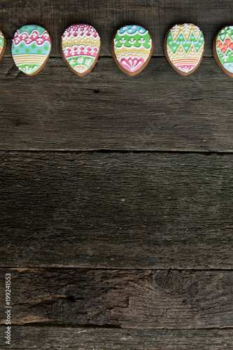 gingerbread cookie in the form of color eggs on dark wooden background.