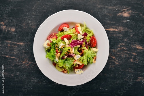 Salad with cheese, nuts and fresh vegetables. On a wooden background. Top view. Copy space for your text.