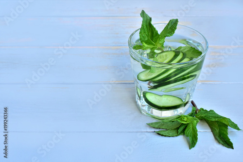 Cucumber detoxing water in a glass, left copy space.