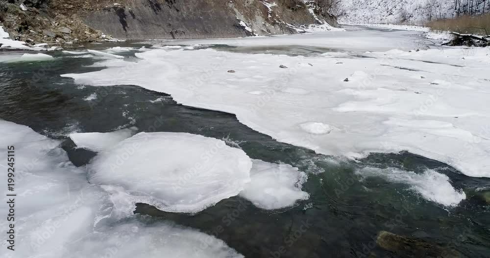 Aerial view og ice melts - the river flows. View of a mountain river in the Carpathians in winter. Aerial view og ice melts - the river flows. View of a mountain river in the Carpathians in winter.
