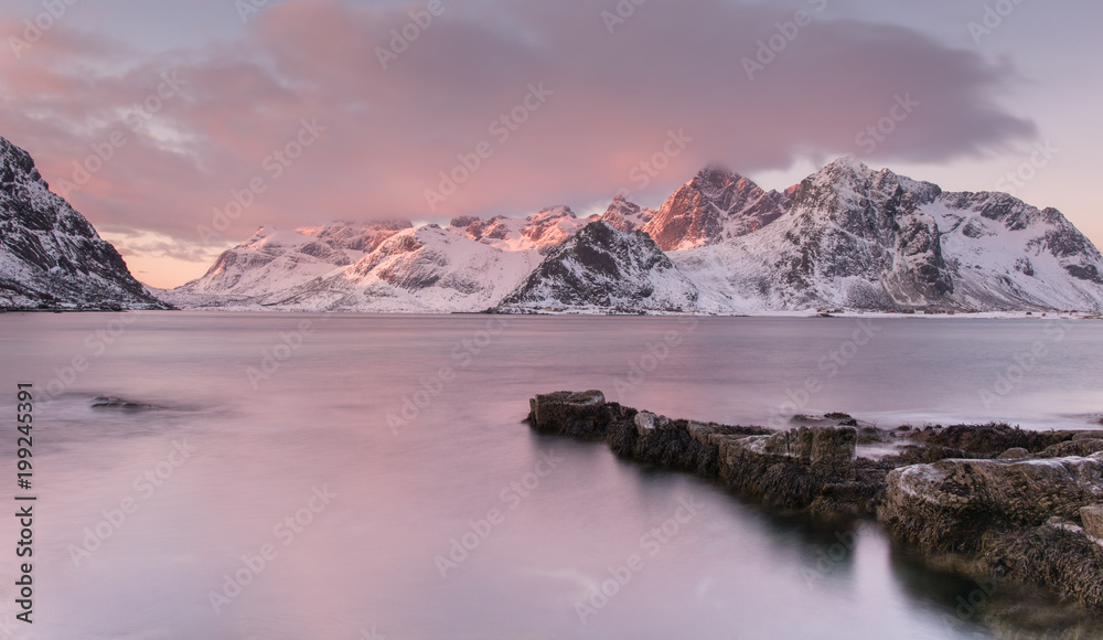 early morning landscape on the shore of fjord with mountains in background