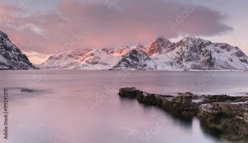 early morning landscape on the shore of fjord with mountains in background