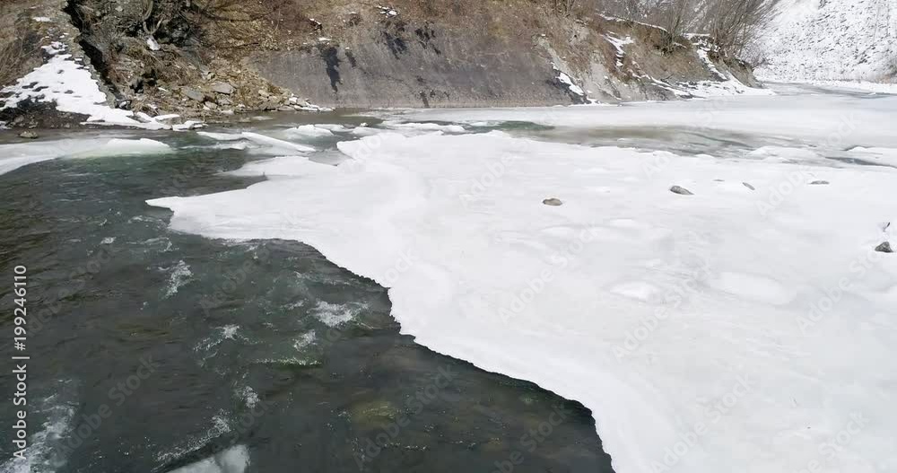 Aerial view og ice melts - the river flows. View of a mountain river in the Carpathians in winter. Aerial view og ice melts - the river flows. View of a mountain river in the Carpathians in winter.