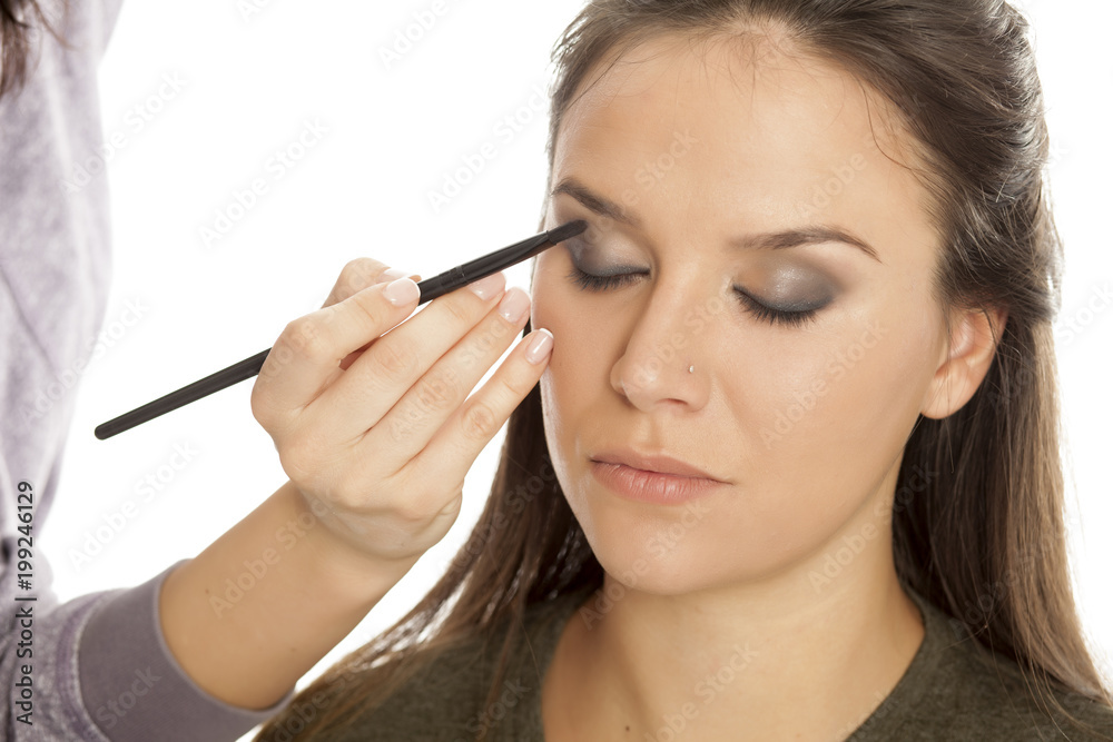 Makeup artist applying eyeshadow with brush on white background Makeup artist applying eyeshadow with brush on white background