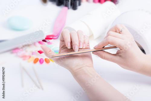 Woman doing manicure with black file on white table