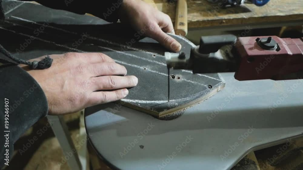 Close up of  joiner hands work with electric saw, man repair skateboard in workshop 