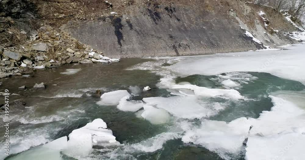 Aerial view og ice melts - the river flows. View of a mountain river in the Carpathians in winter. Aerial view og ice melts - the river flows. View of a mountain river in the Carpathians in winter.