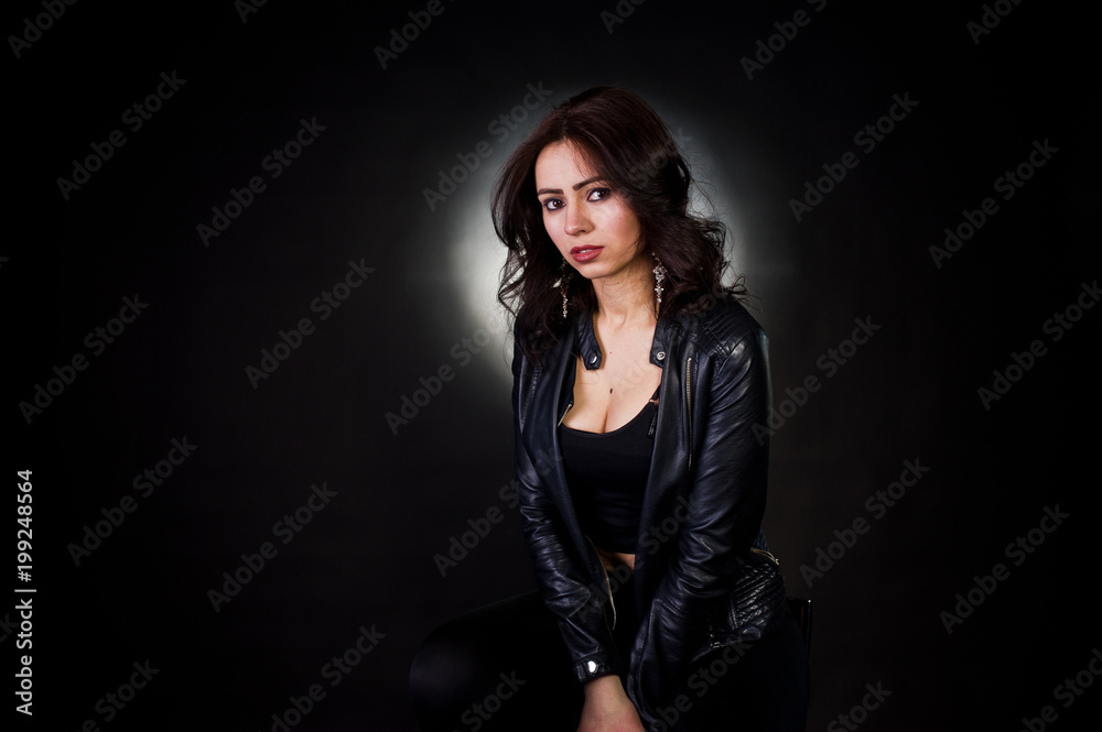 Studio portrait of sexy brunette girl in black leather jacket against black background. Studio portrait of sexy brunette girl in black leather jacket against black background.