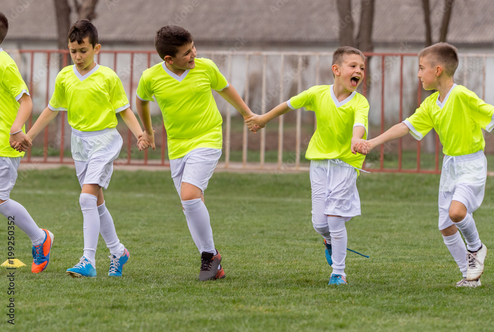 Young children players football holding hands on the field