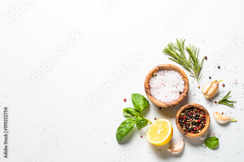 Spices and herbs over white stone table top view.