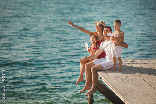 Happy cheerful family at the pier near the water having fun. Adorable kids playing with their parents