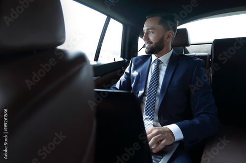 Smiling businessman with laptop sitting in car © ASDF