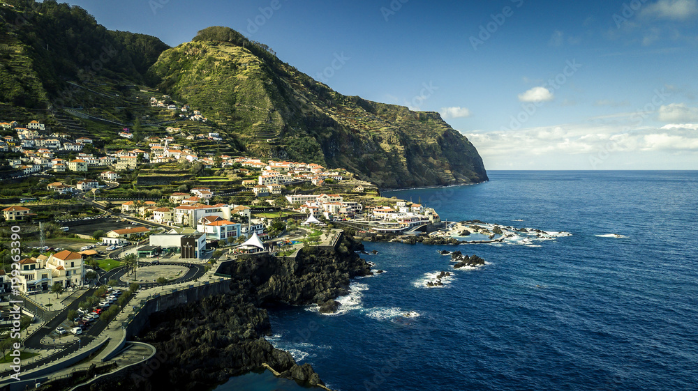 Aerial view on small town Porto Moniz located on Madeira island - red rooftops, coastline, rocks, natural pools. Portugal. Top view from drone.