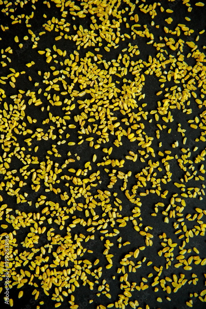 Groats bulgur placer, a pile on a black background is lined in the form of a pattern. The product is rich in protein, healthy food, vegetarianism. View from above