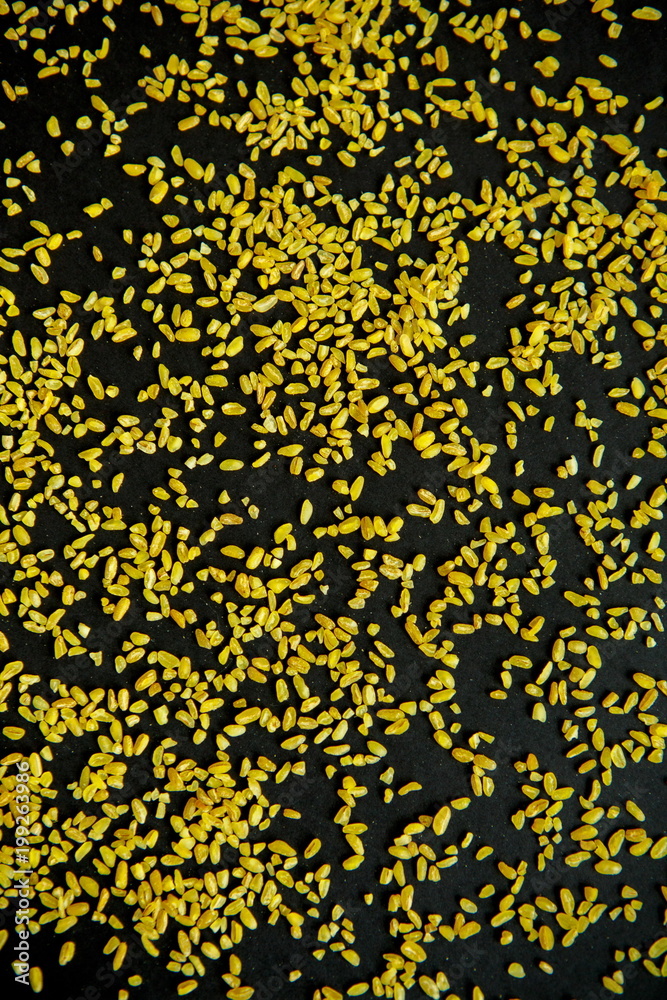 Groats bulgur placer, a pile on a black background is lined in the form of a pattern. The product is rich in protein, healthy food, vegetarianism. View from above Groats bulgur placer, a pile on a black background is lined in the form of a pattern. The product is rich in protein, healthy food, vegetarianism. View from above