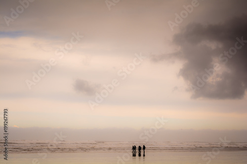 Group of people walking on a sandy beach in wet weather