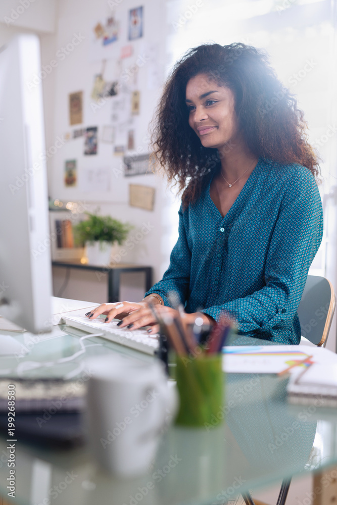 Beautiful young black woman sitting at her desk in front Stock Photo ...