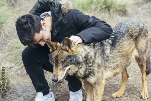 Young handsome man stroking wolf photo