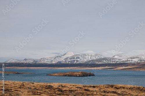 beautiful landscape with rocky mountains covered with snow and cold water of gulf in iceland, hvalfjardarvegur