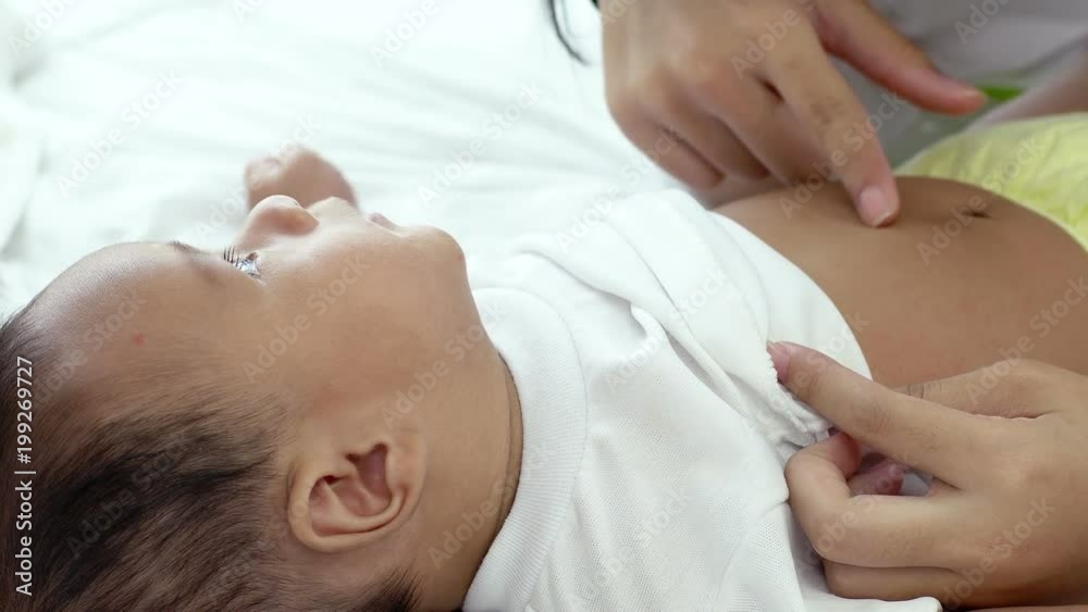 Young beautiful Asian mother caring and playing with her baby in the bedroom on a bright morning sunshine Young beautiful Asian mother caring and playing with her baby in the bedroom on a bright morning sunshine