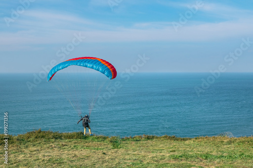 people practicing paragliding with the sea in the background
