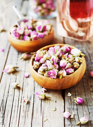 small dry buds of roses, tea, karkade, in wooden bowls, selective focus