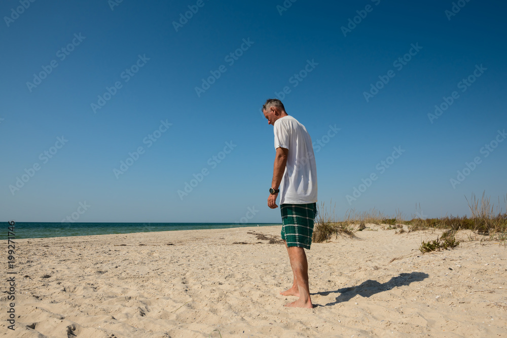 Adventurer, lost in thought, walks along the deserted seashore