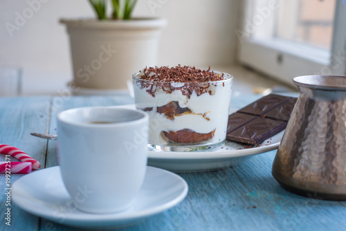 Homemade Italian dessert tiramisu and coffee on the table by the window