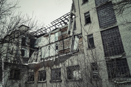 View of a dilapidated brick building. Destroyed brick facade. Toned