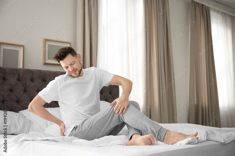 Man suffering from back pain in bedroom Man suffering from back pain in bedroom