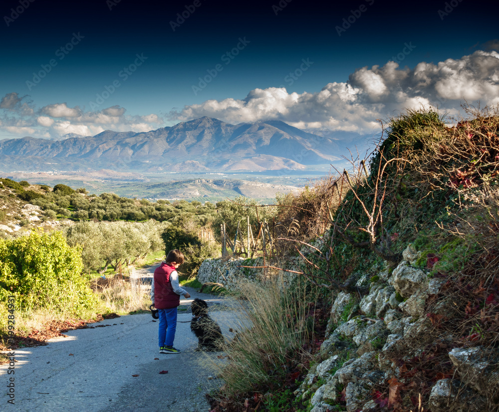 Boy and pet dog on a hill road, Greece