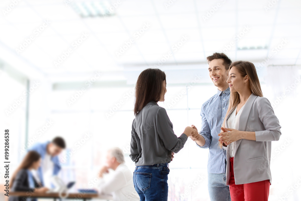 Human resources manager shaking hands with applicant during job interview in office